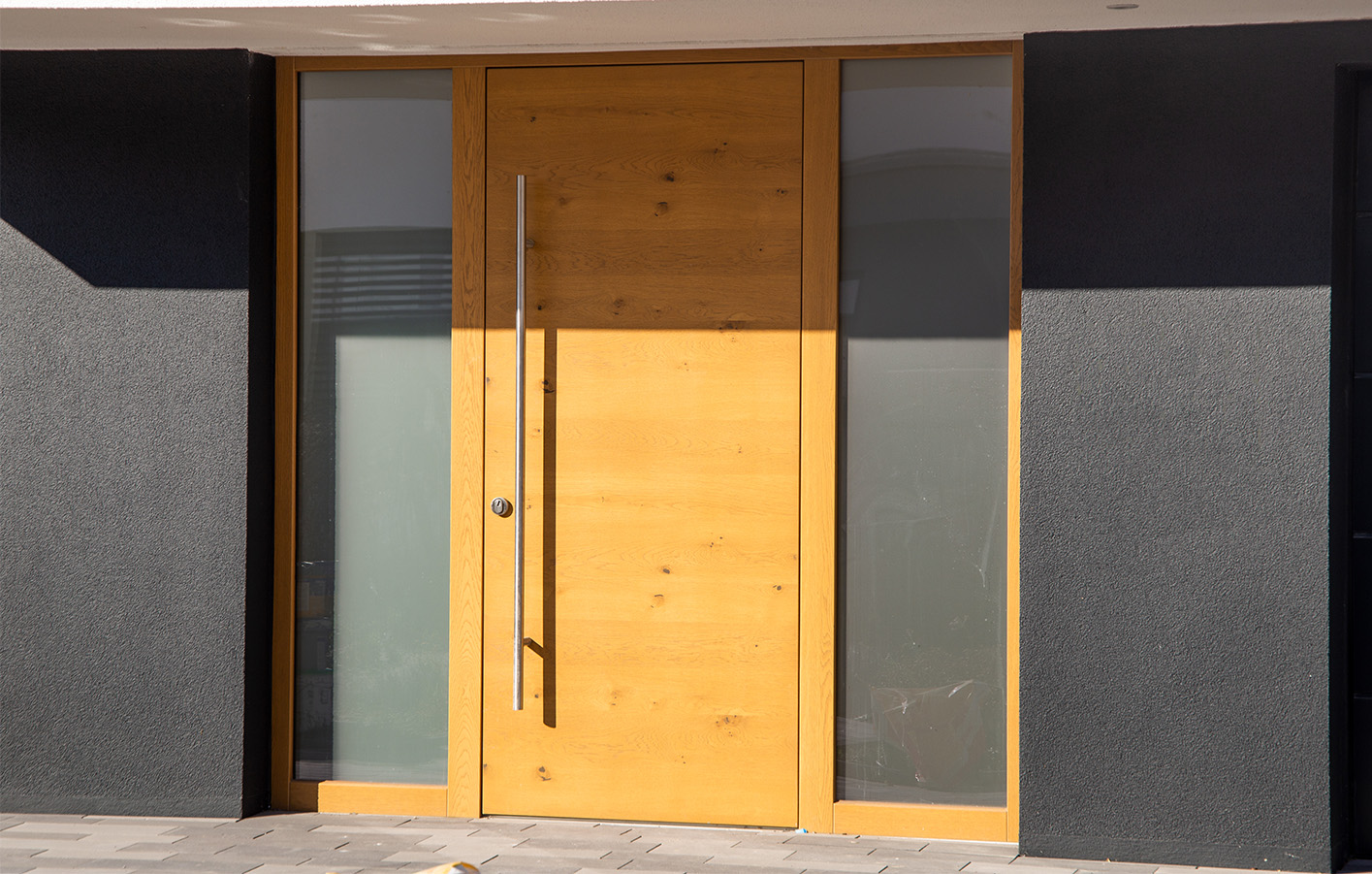 Eleganter Hauseingang mit Holzhaustür und Glaselementen Dunkler Hauseingang mit heller Holzhaustür und seitlichen Glasflächen