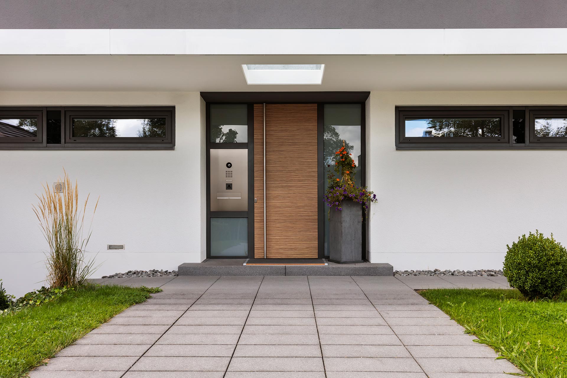 Hauseingang mit Holzoptik-Tür und modernen Glaselementen Moderner Hauseingang mit großflächiger Holzoptik-Tür und Glas-Elementen