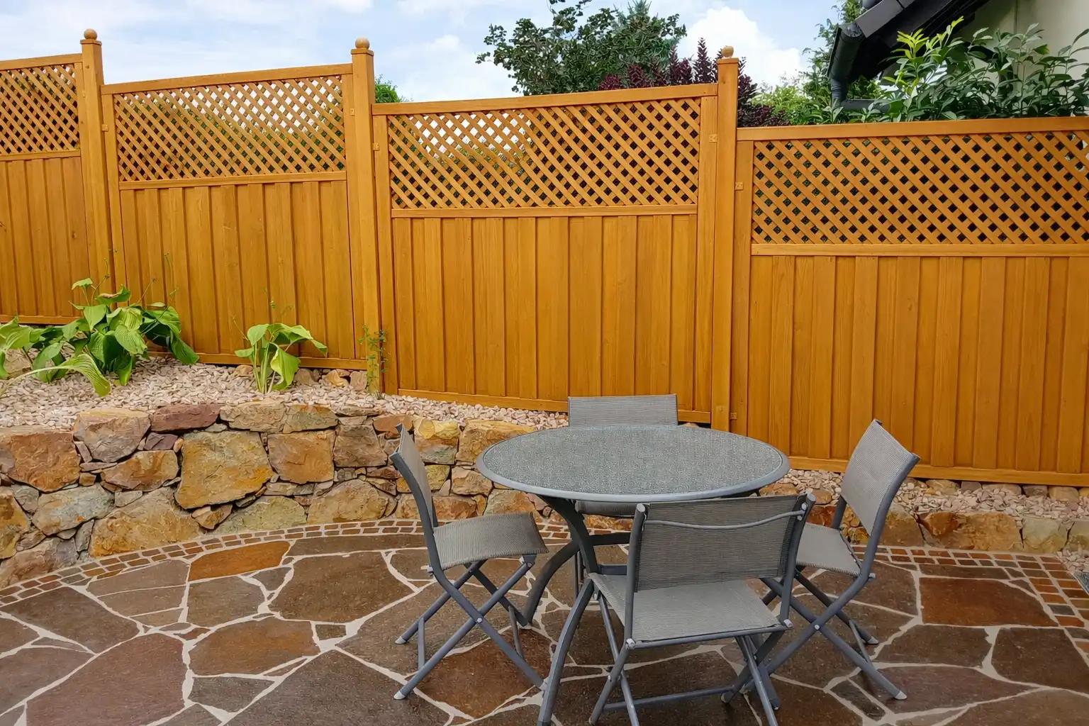 Terrasse mit modernem Holzsichtschutzzaun als Windschutz im Garten eines Einfamilienhauses