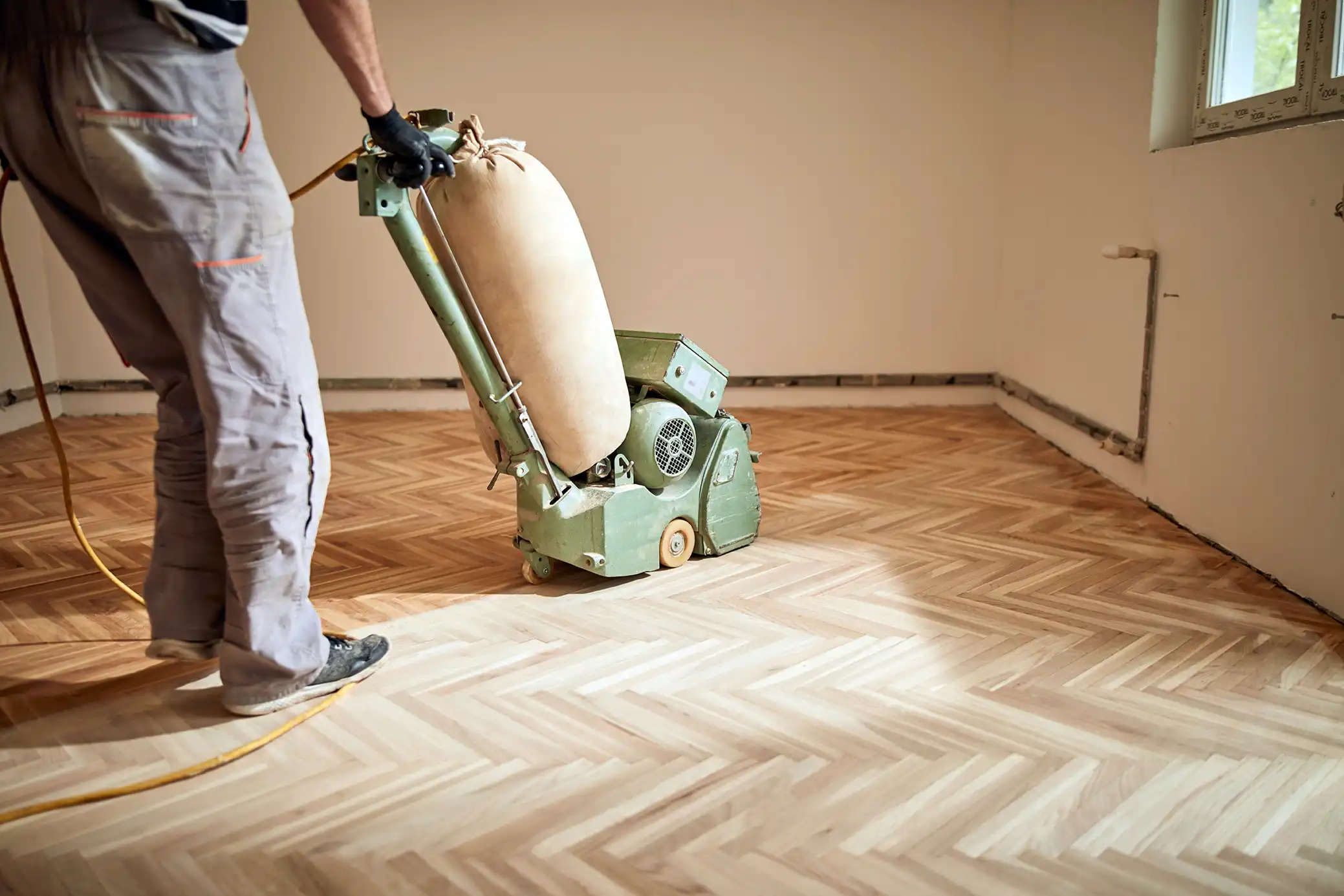 Handwerker schleift einen Parkettboden mit einer Parkettschleifmaschine ab