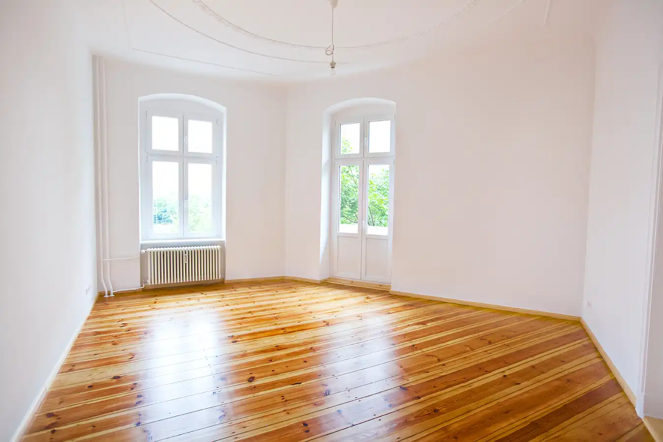 Heller Holzfußboden in einem leeren Raum mit hohen Fenstern