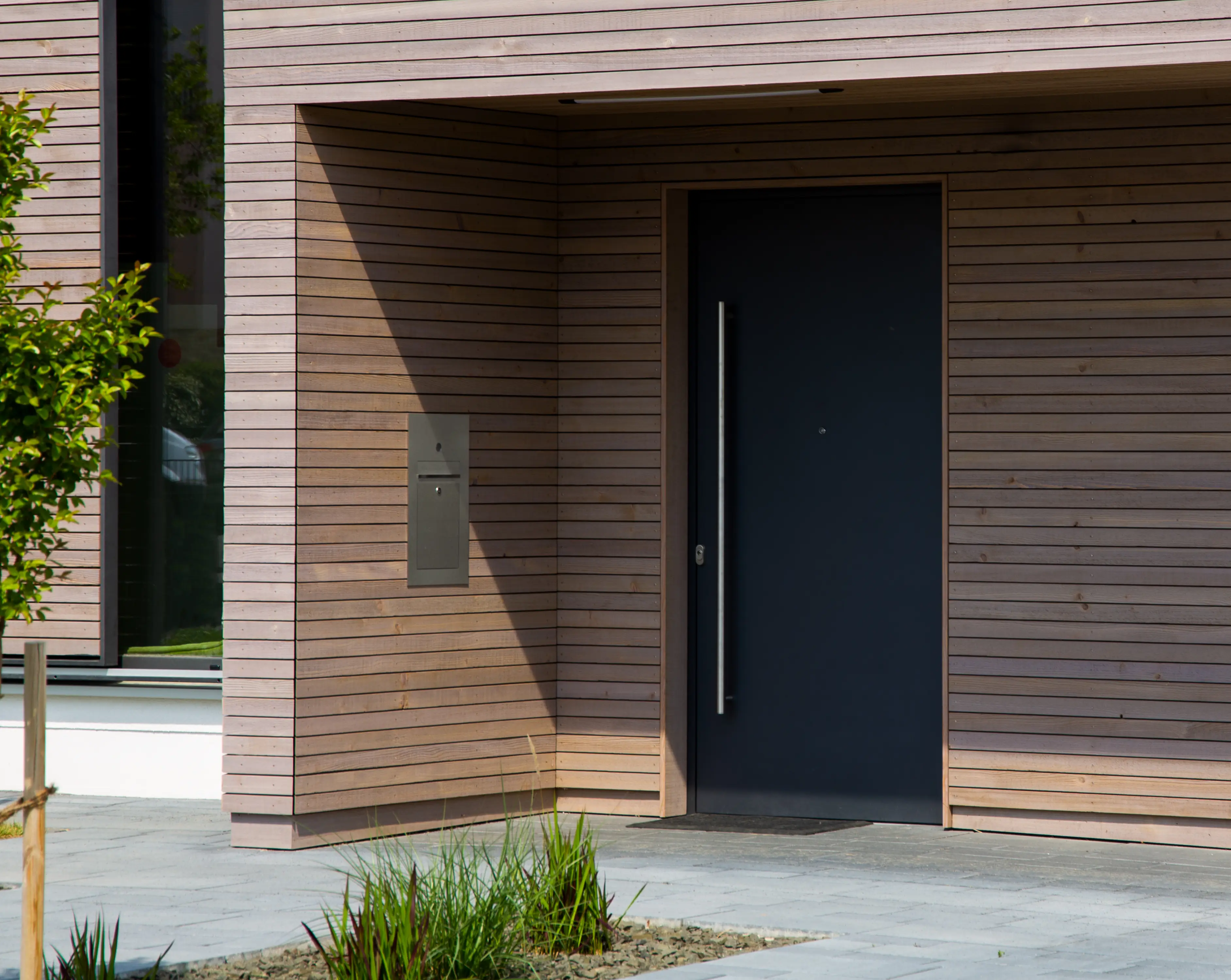 Aluminium-Haustür in moderner Holzfassade integriert
