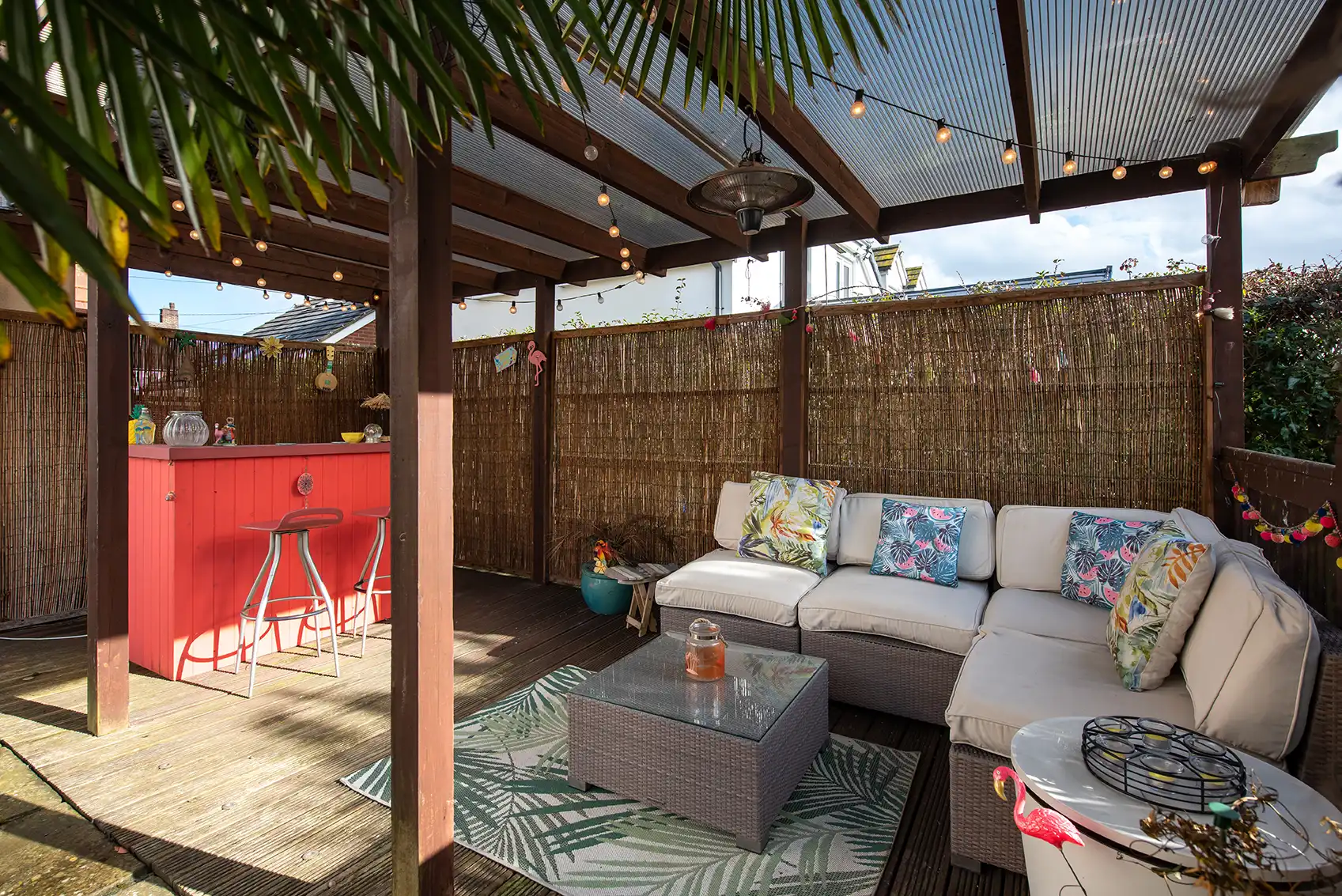 Überdachte Terrasse mit Sitzbereich und farbigem Sichtschutzzaun